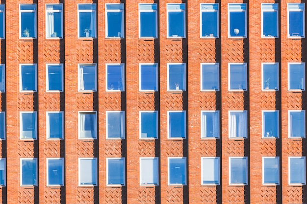 Fachada de edificio de ladrillos de color naranja y ventanas.