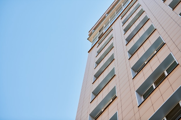 Fachada de edificio de varios pisos, espacio de copia. Ritmo en fotografía. Nueva fachada de varios pisos, ventanas y bloque de pisos, de cerca. Apartamentos modernos en edificio alto