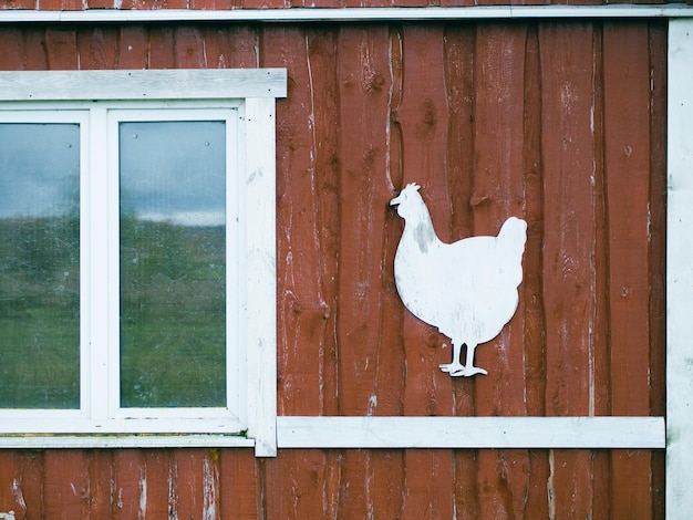 fachada de gallinero de madera rústica roja con estencil de pollo para el concepto de cultivo de texto