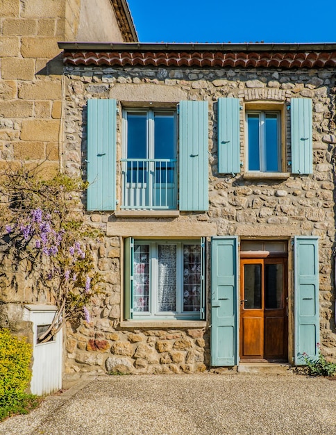 fachada de una hermosa casa de piedra en Boucieu le Roi (Ardeche, Francia) con persianas azules