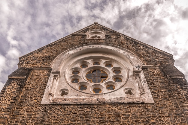 Fachada de la iglesia católica con un primer plano de fondo de cielo nublado.