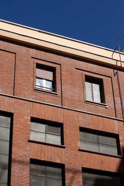 Fachada de ladrillo rojo con ventanas industriales y cielo azul profundo