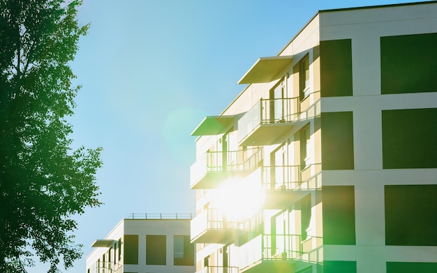 Fachada del moderno edificio residencial de apartamentos. Incluyendo lugar para espacio de copia. Y las hojas de los árboles verdes y la luz del sol