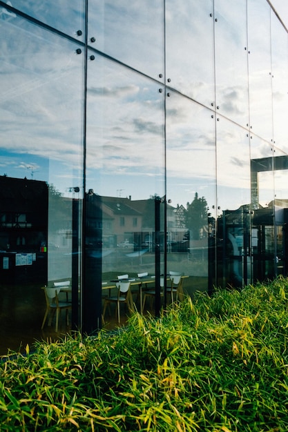 Foto la fachada de un moderno edificio de vidrio de oficinas que refleja la hierba exuberante y las casas residenciales en el suburbio foto