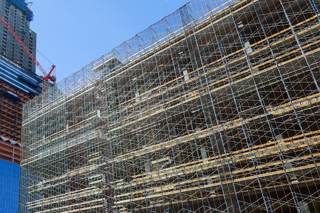 Fachada del nuevo proceso de construcción de rascacielos de propiedad comercial para líneas de montaje de andamios que cubren la fachada del edificio.