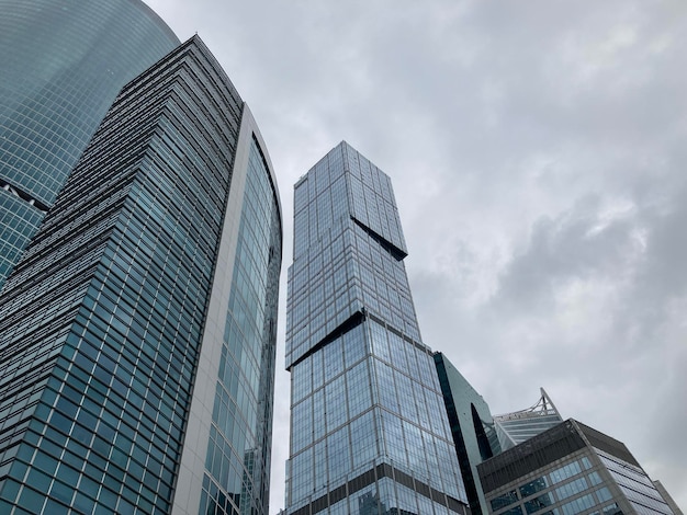 Fachada de un rascacielos moderno con paredes de cristal Desde abajo de un rascacielos alto contemporáneo con paredes de cristal contra el cielo nublado en el centro