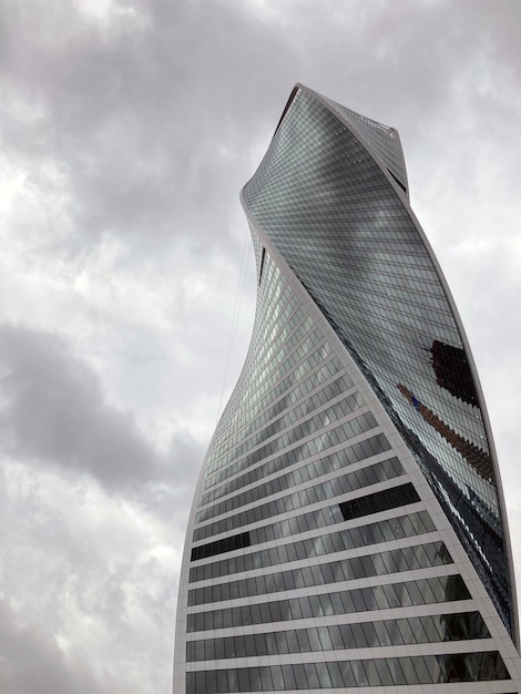 Fachada de un rascacielos moderno con paredes de cristal Desde abajo de un rascacielos alto contemporáneo con paredes de cristal contra el cielo nublado en el centro