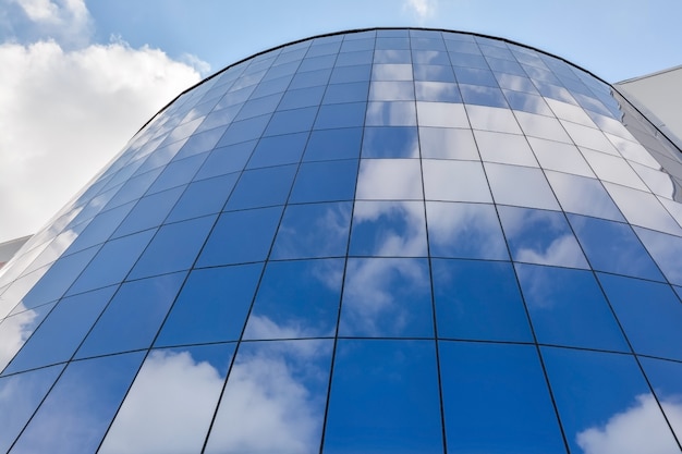 Fachada de vidrio de un moderno edificio de oficinas contra un cielo azul con nubes