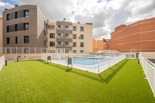 Fachadas de casas residenciais urbanas com piscina comunitária e grama artificial em um dia ensolarado com nuvens cheias de água