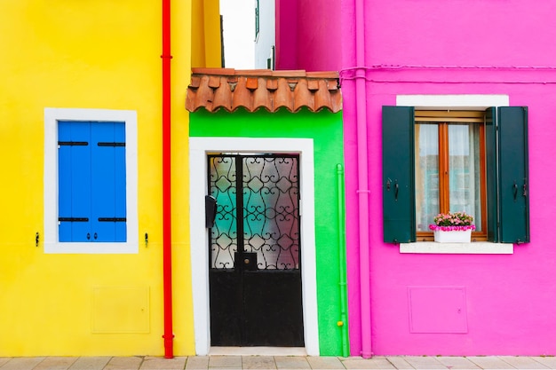 Fachadas pintadas de amarillo y rosa de las casas y ventanas con persianas de colores. Burano, Italia