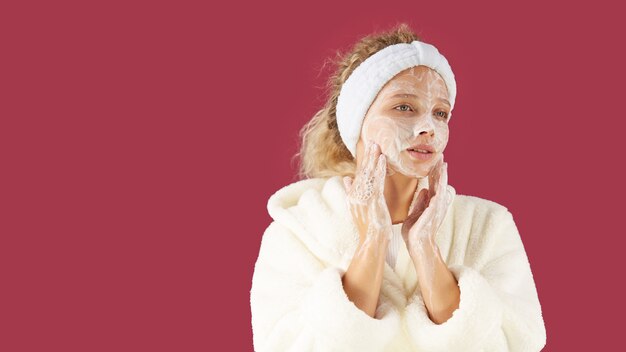 Facial. Una niña con una bata de Terry y una máscara en el rostro.