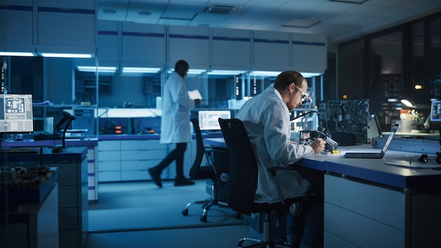Facilidad moderna de investigación y desarrollo de electrónica Ingeniero caucásico inteligente soldado de placas base de computadoras Científicos diseñan PCB industriales microchips de silicio semiconductores