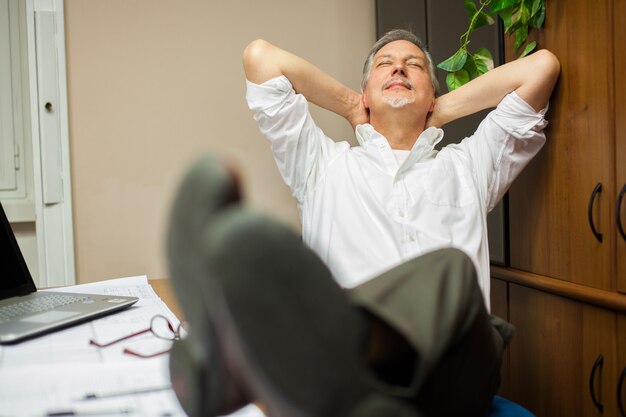 Fälliger Geschäftsmann, der in seinem Büro sich entspannt