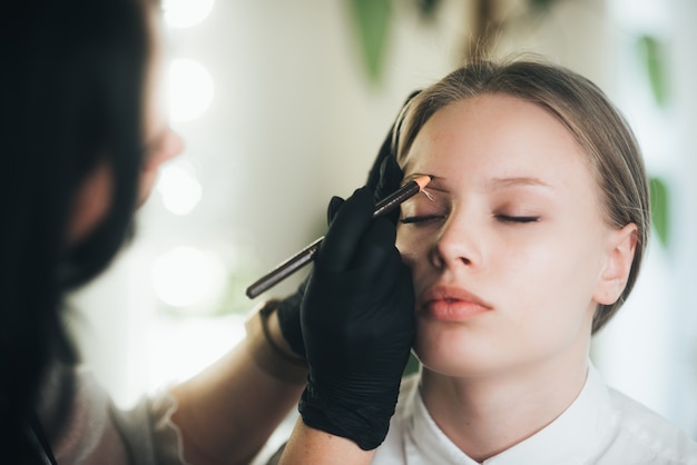 Färben und Formen von Augenbrauen. Mädchen in einem Schönheitssalon.