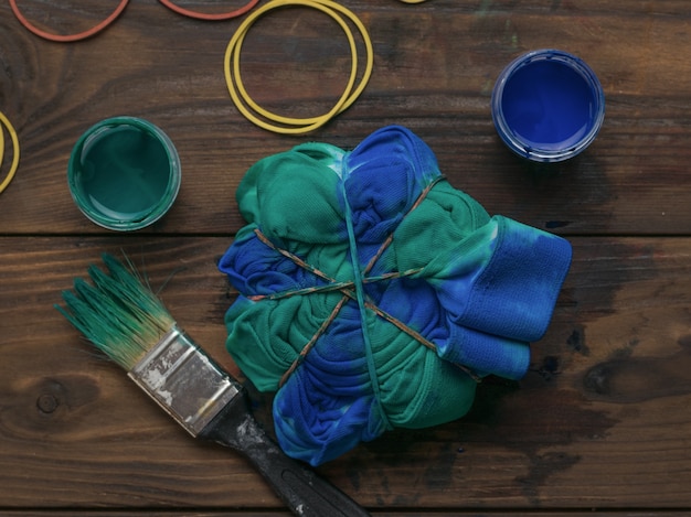 Färben von Kleidung im Tie-Dye-Stil mit blau-grüner Farbe. Färben von Stoff im Tie-Dye-Stil.