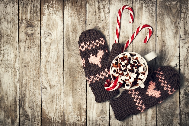 Fäustlinge mit Herzen und einer Tasse Kaffee mit Schokolade und Marshmallows