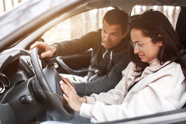 Fahranweisung. Eine junge Frau lernt zum ersten Mal Autofahren. Sie arbeitet nicht gut. Ihr Mann oder Ausbilder schreit sie an. Sie weint