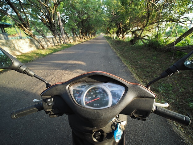 Fahren Roller bei Sonnenaufgang Licht auf leere ländliche Asphaltstraße. POV.