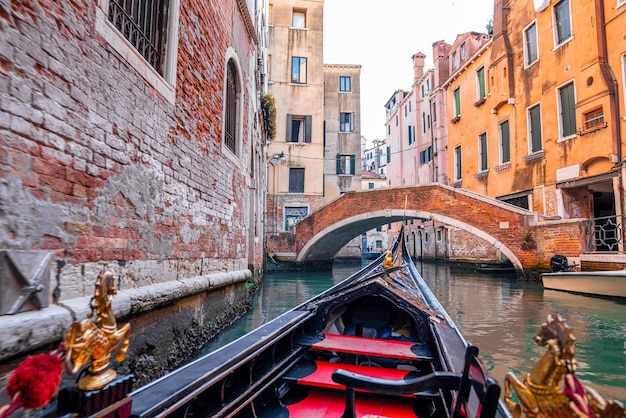 Fahren Sie mit einer traditionellen Gondel durch die engen Kanäle in Venedig, Italien. Retro-Vintage-getönten Instagram-Stil-Grunge-Filter und Lens Flare-Sonnenlicht-Effekt.