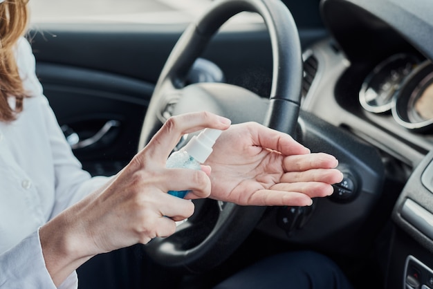 Fahrer Desinfektion Hände mit antibakteriellem Spray im Auto vor dem Fahren