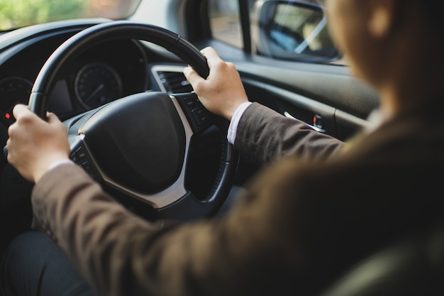 Fahrer im Anzug, der ein Auto mit der Hand am Steuer fährt