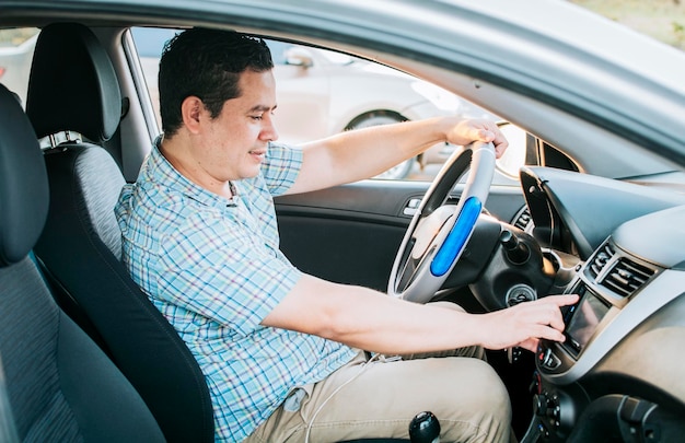 Fahrermann, der den Radiosender wechselt Lächelnder Fahrer, der sich auf den Radiosender einstellt Abgelenktes Fahrerkonzept, das das Radio einstellt Fahrende Menschen, die den Radiosender wechseln