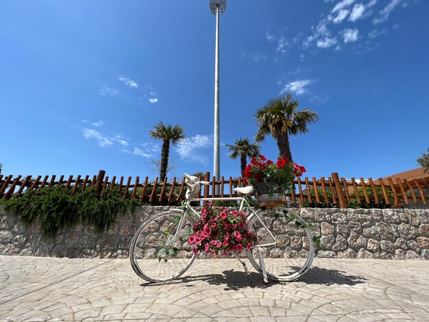Fahrrad mit Blumenkorb steht in der Nähe eines Holzzauns