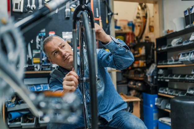 Foto fahrradmechaniker, der ein fahrrad in der werkstatt trägt