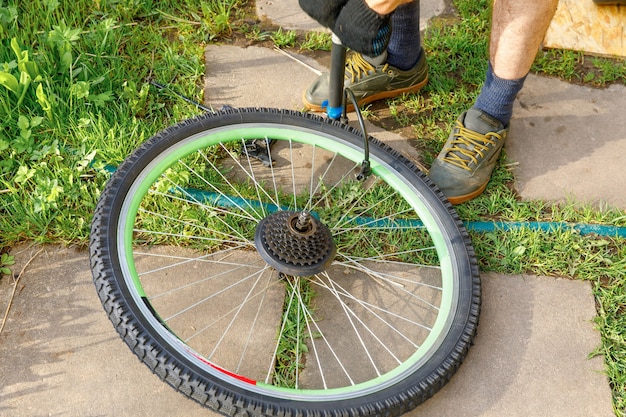 Fahrradmechaniker repariert Fahrrad in Fahrradwerkstatt, im Freien. Hand des Radfahrers Fahrradfahrer untersucht, repariert modernes Fahrradübertragungssystem. Fahrradwartung, Sportgeschäftskonzept.