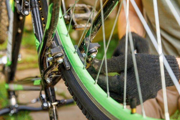 Fahrradmechaniker repariert Fahrrad in Fahrradwerkstatt, im Freien. Hand des Radfahrers Fahrradfahrer untersucht, repariert modernes Fahrradübertragungssystem. Fahrradwartung, Sportgeschäftskonzept.