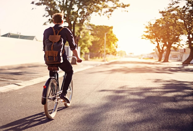 Fahrradtransport und Rücken eines Mannes auf der Straße mit Blendenfleck für sportliche Betätigung beim Pendeln und Radfahren am Morgen Reisen Sie durch die Stadt und männlicher Radfahrer auf dem Fahrrad für umweltfreundliches Reisen, CO2-Fußabdruck und Reise