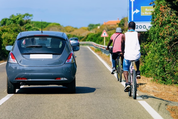 Fahrräder und Autos auf der Straße an der Costa Smeralda auf der Insel Sardinien in Italien im Sommer. Biker fahren Roller auf der Autobahn in Europa. Blick auf Fahrräder auf der Autobahn.