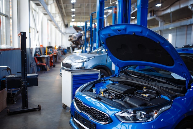 Fahrzeug mit geöffneter Motorhaube am Wagenheber, Autotankstelle, niemand. Innenraum der Autowerkstatt, Prüf-, Diagnose- und Reparaturausrüstung