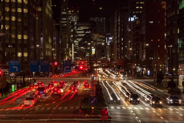 Fahrzeuge mit Lichtspuren auf einer Stadtstraße inmitten von Gebäuden