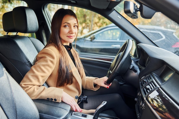 Fahrzeuginnenraum Frau sitzt in modernem schwarz gefärbtem Automobil