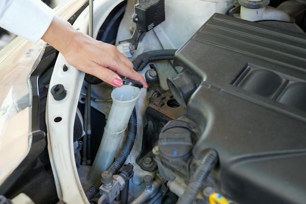 Fahrzeugsicherheitskonzept Womans Hand Überprüfung des Automotors vor der Fahrt Autowartung Glasreiniger