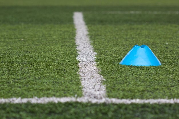 Faixa branca com cone para treino no campo de futebol verde