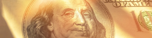 Faixa larga de notas de dólar, rosto de benjamin franklin em close-up de raios de sol, foto de fundo de negócios e bancos