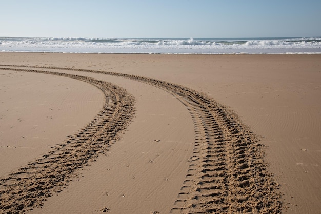 Faixas na costa da praia, traço de carro dourado na areia do Oceano Atlântico