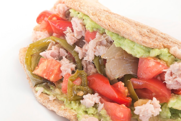 Fajitas con mezcla de tortilla de tomate, pimiento, atún, cebolla y aguacate sobre fondo blanco.