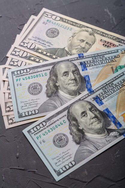 Un fajo avivado de billetes de ciento cincuenta dólares sobre un fondo gris. Foto vertical