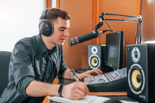 Foto fala e usa microfone jovem está dentro de casa no estúdio de rádio está ocupado por transmissão