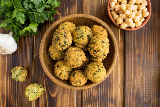 Falafel de grão de bico na tigela marrom na madeira