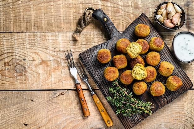 Falafel de garbanzos con salsa tzatziki sobre una tabla de madera.