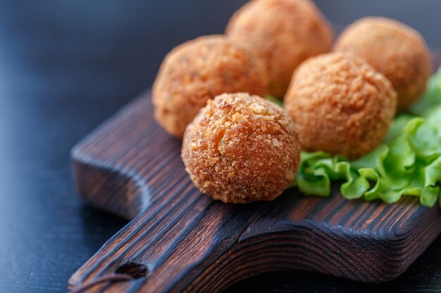 Falafel liegt auf einem Holzbrett.