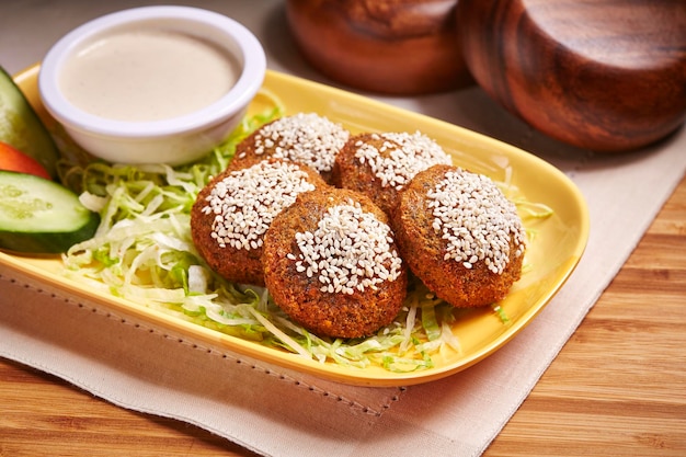 Falafel ou falafil com salada e molho servido em prato isolado na mesa vista lateral da comida do oriente médio