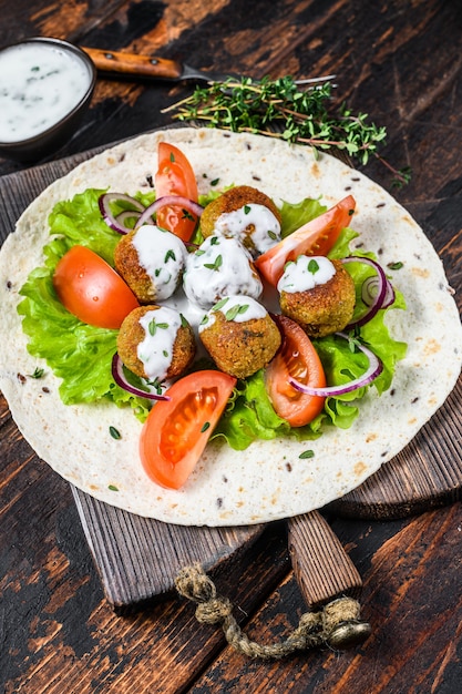 Falafel vegetariano con verduras y salsa tzatziki sobre pan de tortilla