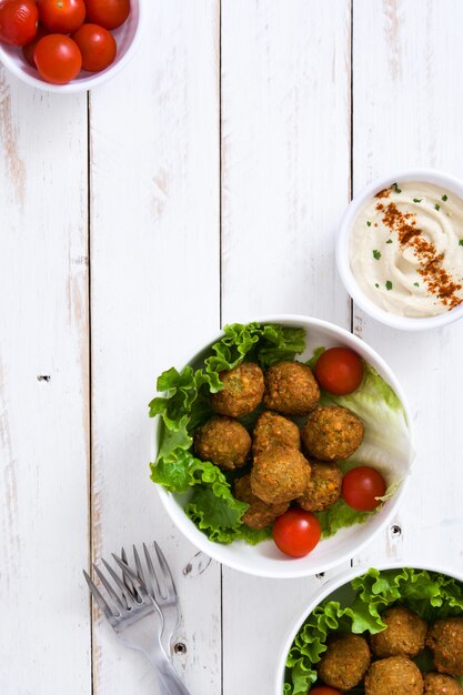 Falafels vegetarianos na tigela e hummus na vista superior de madeira branca