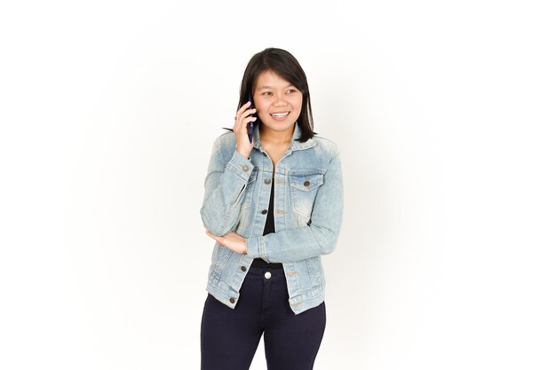 Falando ao telefone de uma linda mulher asiática vestindo jaqueta jeans e camisa preta isolado no branco