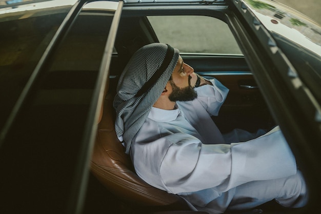 Falando em um carro Homem saudita sentado em um carro e falando ao telefone